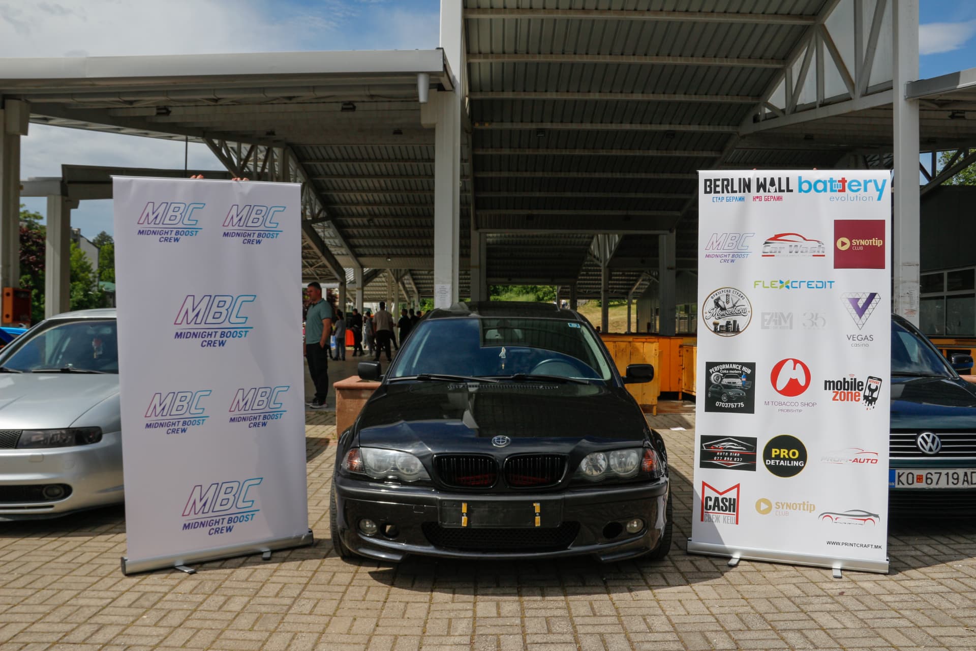 Black BMW sedan between MBC banners
