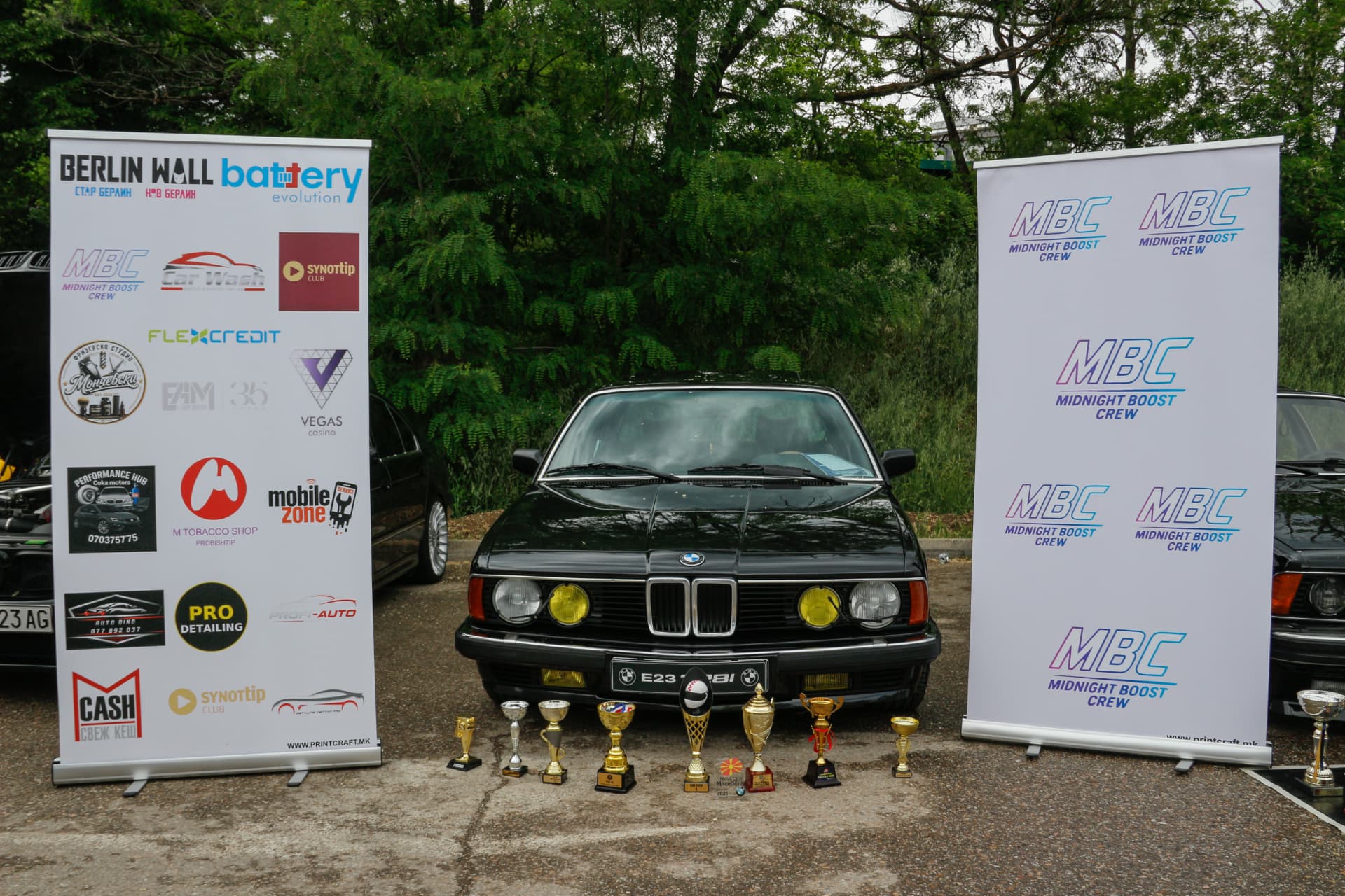 Black BMW E23 with trophies between MBC and sponsor banners
