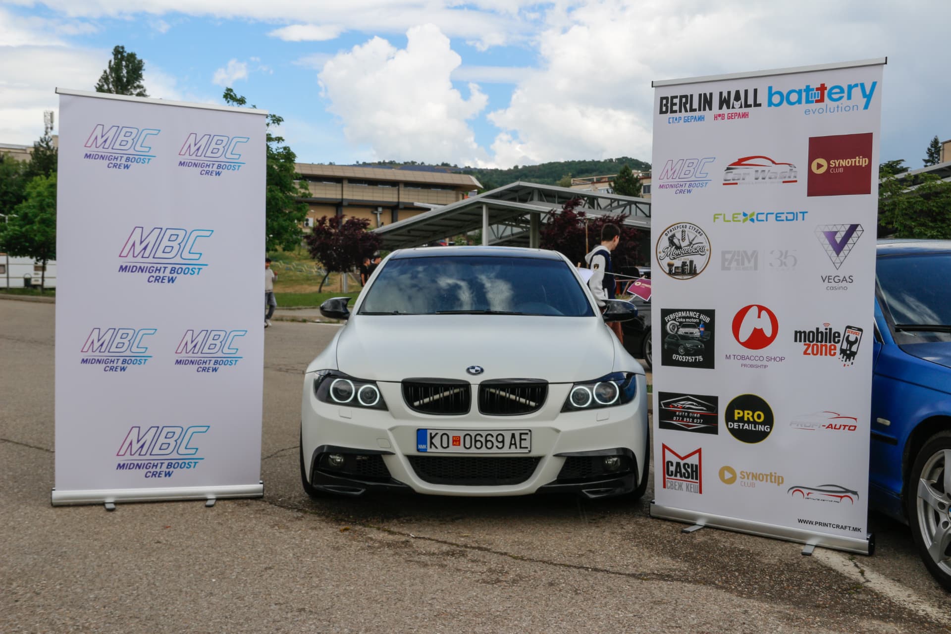 White BMW E90 with black grille between MBC and sponsor banners