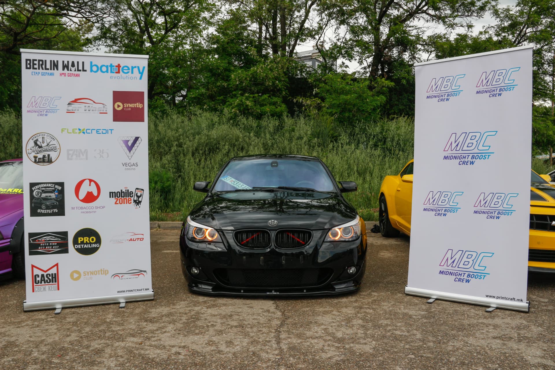 Black BMW E60 with orange angel eyes between MBC and sponsor banners