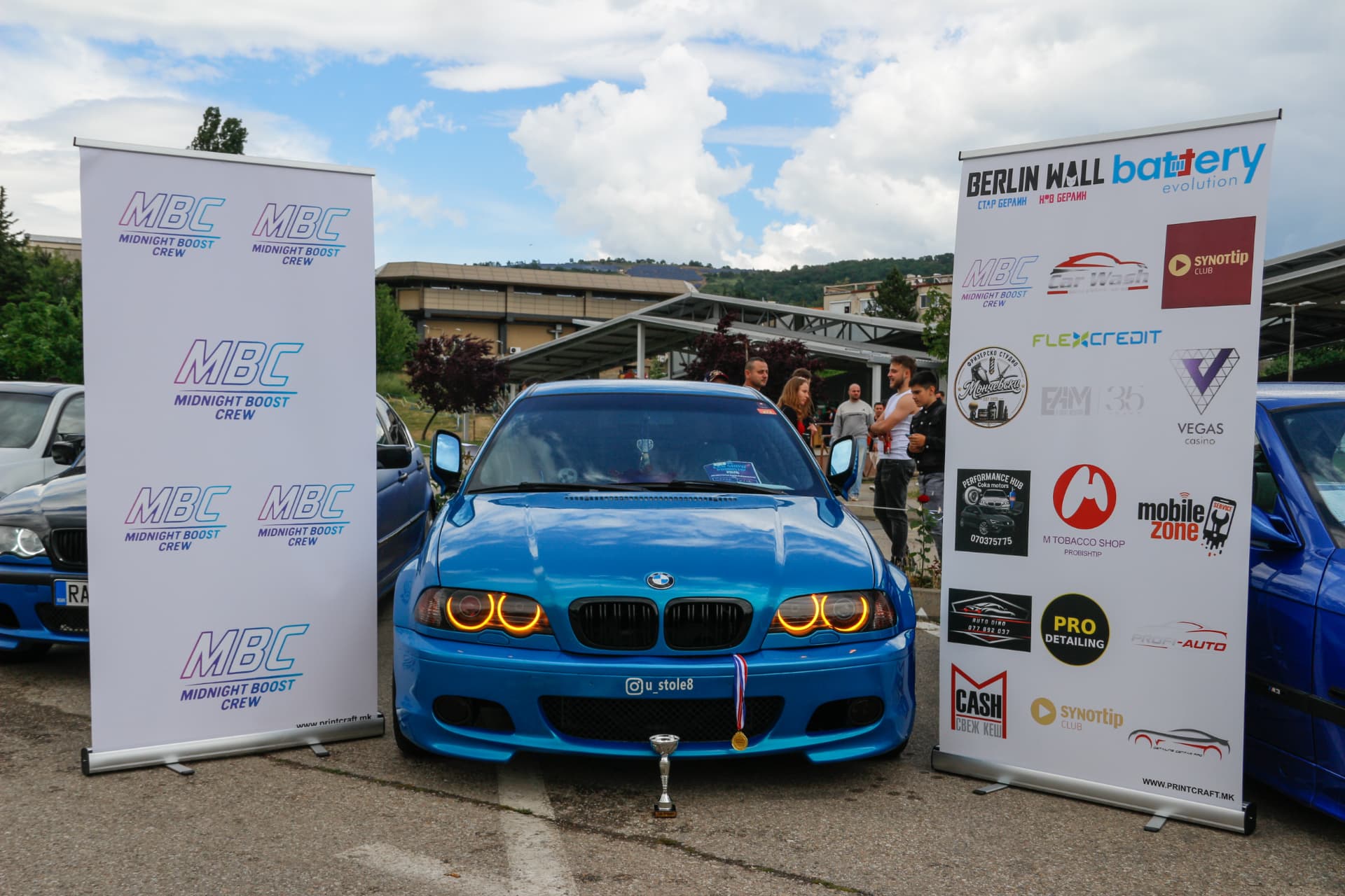 Blue BMW E46 with trophy and medal between MBC and sponsor banners