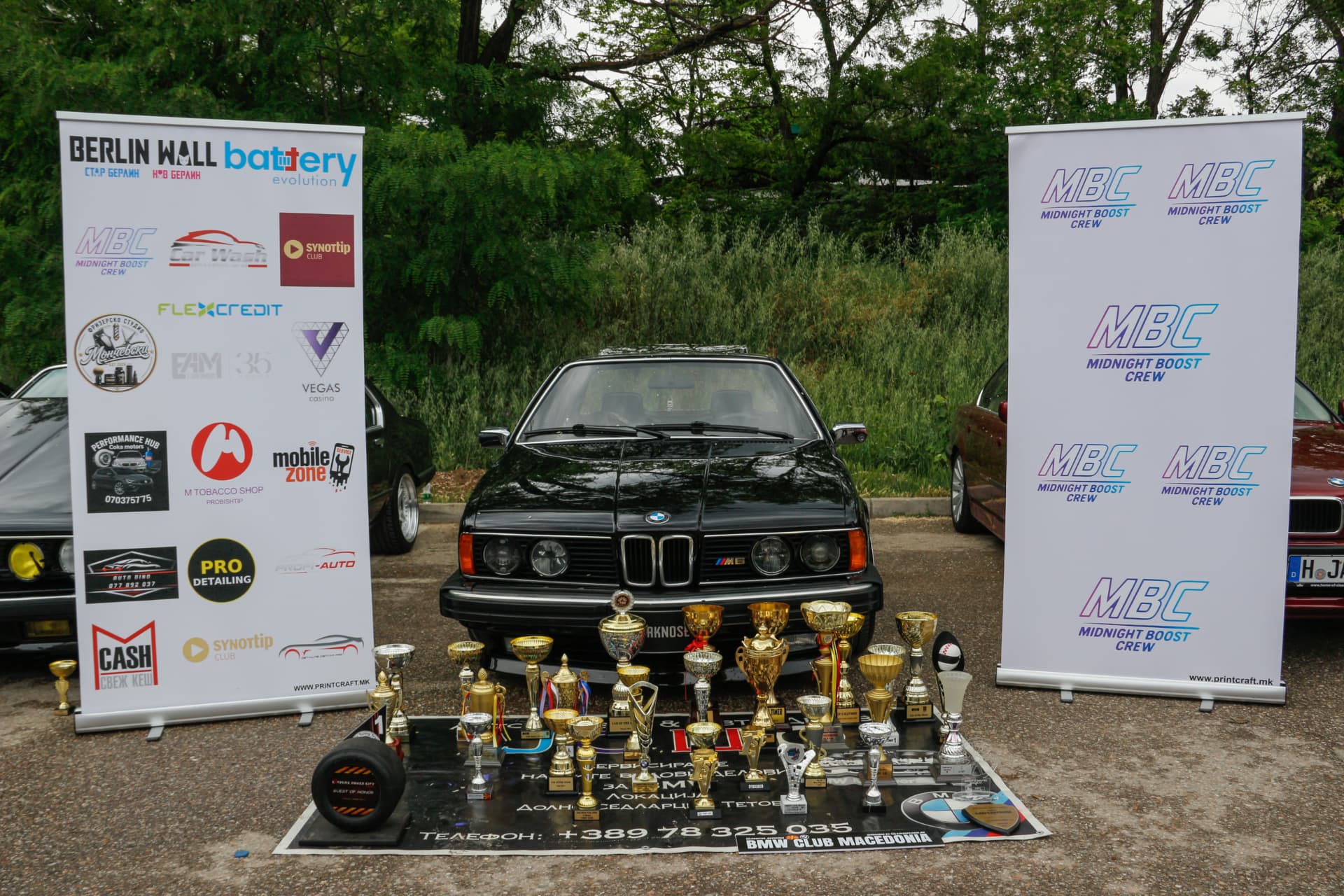 Black BMW E24 with trophy collection between MBC and sponsor banners